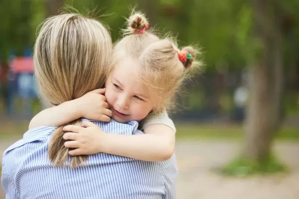 Toddler Girl Hugging Woman As She's Holding Her