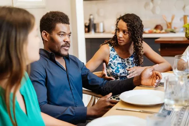 A group of friends engaging in a cheerful conversation while sitting around a dinner table, sharing a moment of togetherness.