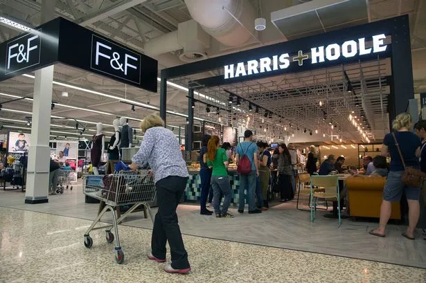 A customer pushes a shopping cart past a Harris and Hoole coffee shop and a F&F fashion outlet inside a Tesco Plc store