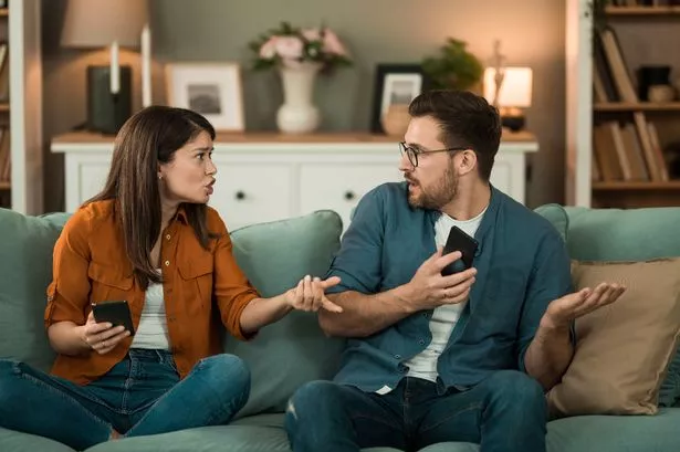 A man and woman talking on a sofa