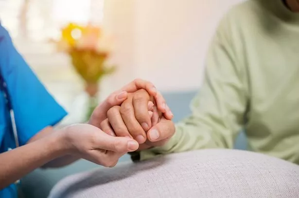 A Young Woman Holding An Older Man's Hand.
