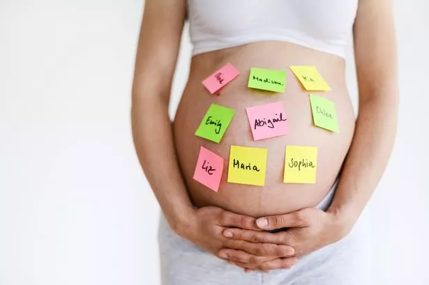 Young pregnant woman has a lot of posts with female names sticking on her pregnant belly. Illustrating today's problems of parents finding the right name for their unborn child