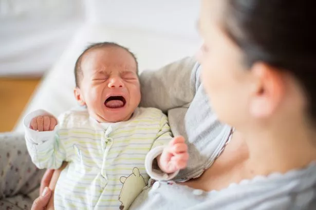 A MUM HOLDING A CRYING BABY