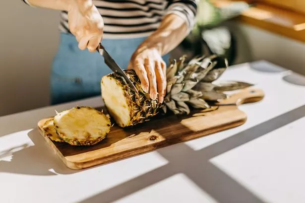 Woman cutting pineapple on desk