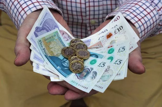 Man Holding Pound Coins and Notes in Five, Ten, Twenty and Fifty Denominations, in Both Hands.