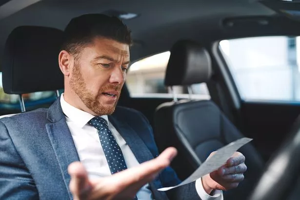 Cropped Shot of a handsome mature businessman look at his his parking ticket while sitting in the driver's seat of his car