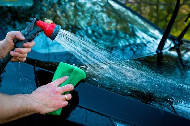 Closeup picture, image young woman, driver, dry wiping her car with microfiber cloth after washing it