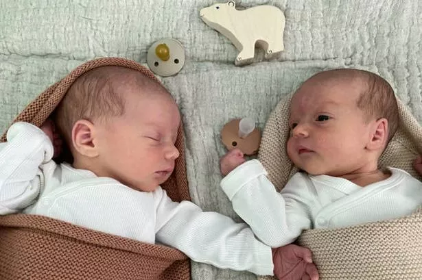 New born baby boy and girl laying next to each other (stock photo)
