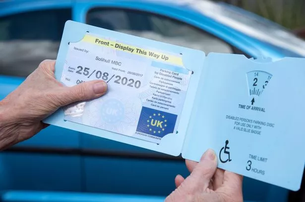 Woman's Hands Holding A Blue Badge Parking Discics in the uk to disabled drivers. 