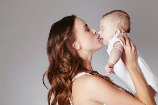 Mother kissing baby daughter