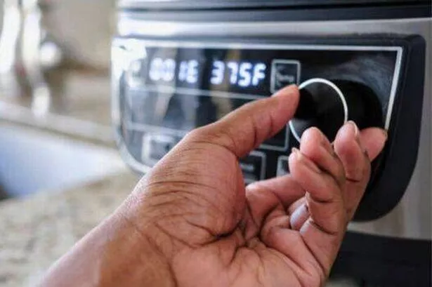 Image of an Air Fryer, With A Hand Spinning The Dial Up