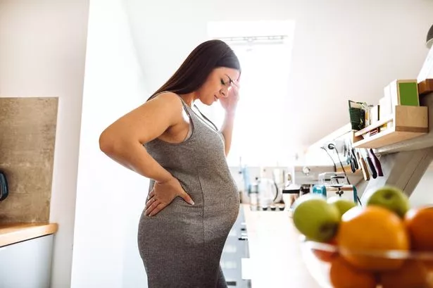 A Pregnant Woman Looking Upsen In A Kitchen
