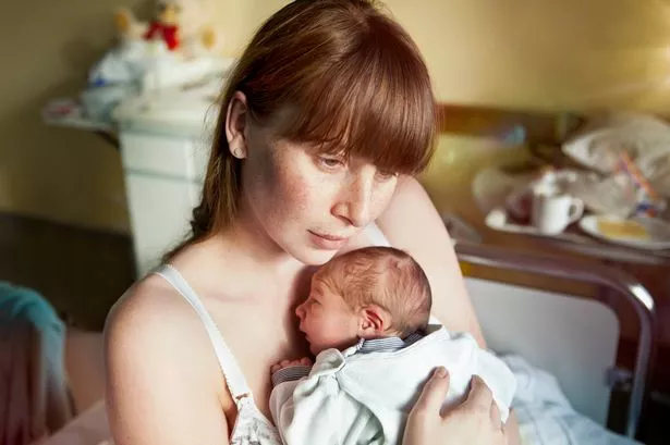 A SAD MUM HOLDING HER BABY