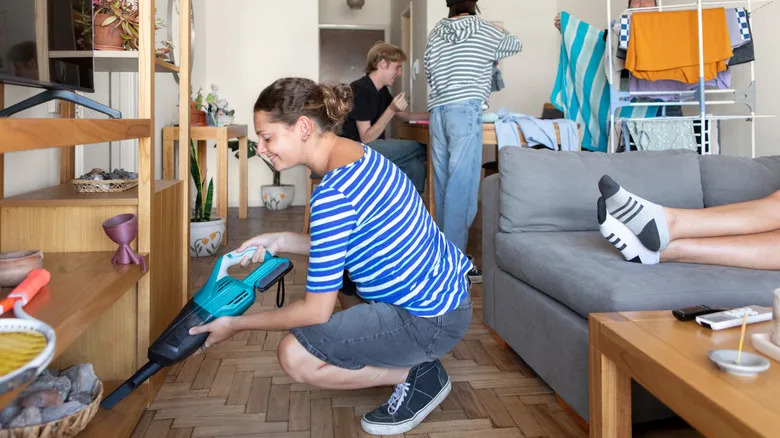 People cleaning house with one person vacuuming