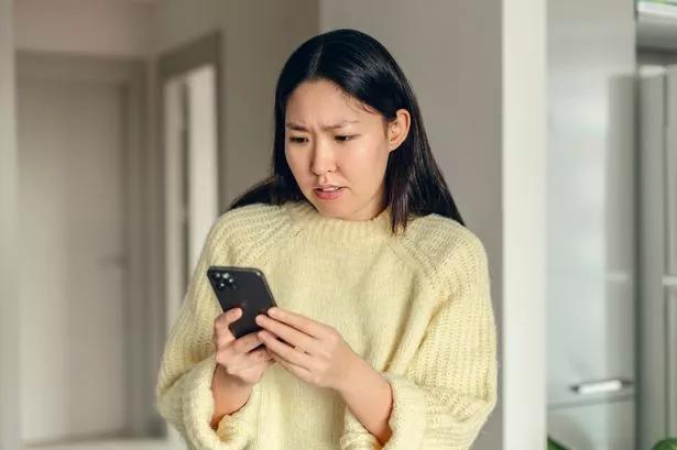 Young woman looking confused at her mobile phone