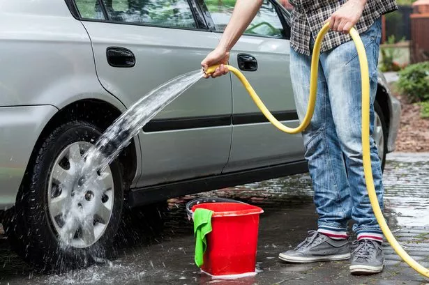Man cleaning car in front of house