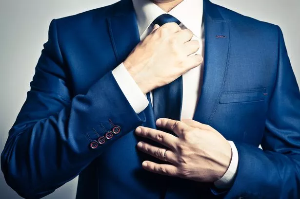 Businessman in blue suit adjusting his tie