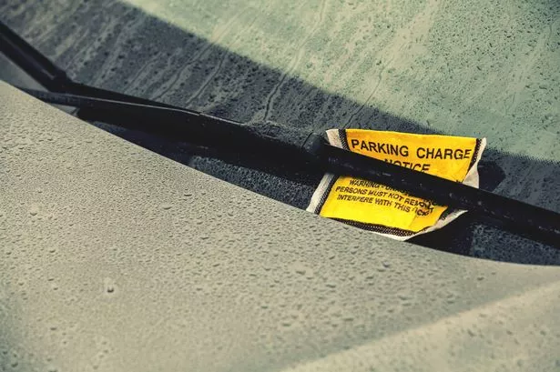 Parking charge ticket under wiper on car on a wet day
